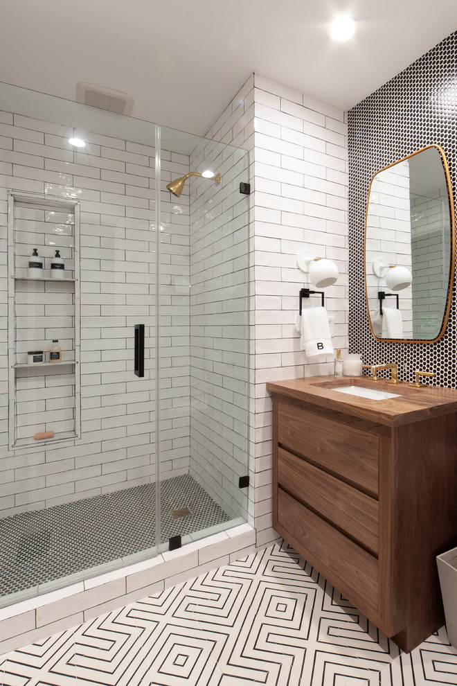 Example of a country 3/4 black and white tile and subway tile white floor corner shower design in Charlotte with flat-panel cabinets, medium tone wood cabinets, an undermount sink, wood countertops, a hinged shower door and brown countertops