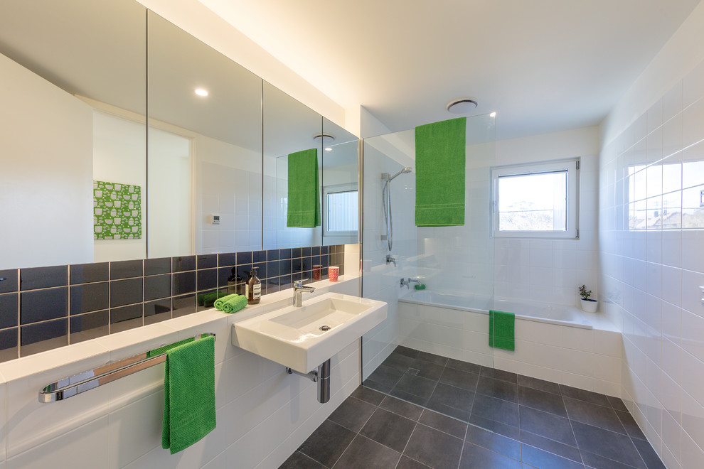 Idéer för ett litet modernt en-suite badrum, med ett badkar i en alkov, en öppen dusch, vit kakel, keramikplattor, vita väggar, klinkergolv i keramik, ett väggmonterat handfat och grått golv