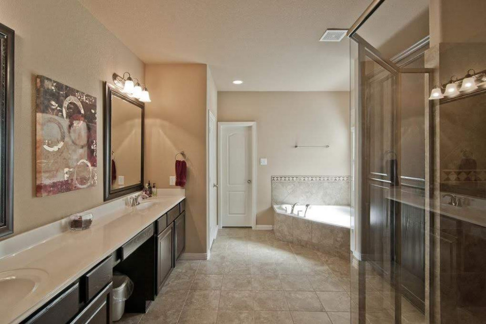 На фото: главная ванная комната в классическом стиле с фасадами с выступающей филенкой, коричневыми фасадами, угловой ванной, угловым душем, раздельным унитазом, бежевой плиткой, керамической плиткой, бежевыми стенами, полом из керамической плитки, монолитной раковиной, мраморной столешницей, бежевым полом, душем с распашными дверями и белой столешницей с