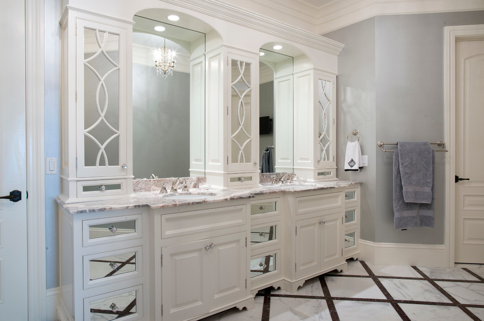 Aménagement d'une très grande salle de bain principale classique avec un placard à porte affleurante, des portes de placard blanches, un plan de toilette en granite, une baignoire posée, un carrelage blanc, un carrelage de pierre, un mur gris et un sol en marbre.