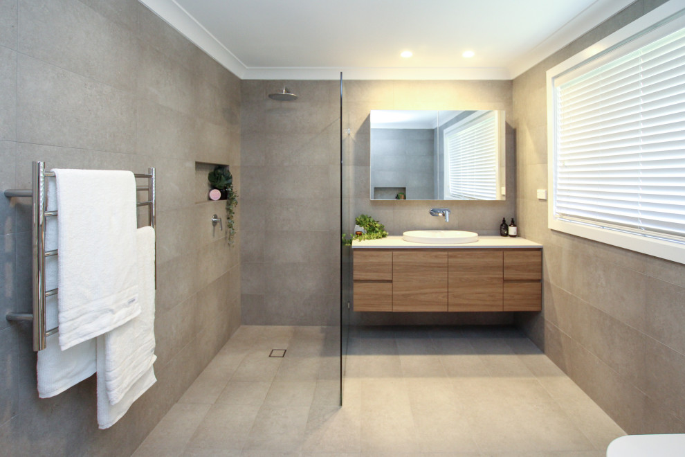 Идея дизайна: большая главная ванная комната в стиле модернизм с светлыми деревянными фасадами, отдельно стоящей ванной, открытым душем, раздельным унитазом, серой плиткой, открытым душем, белой столешницей, тумбой под одну раковину и подвесной тумбой