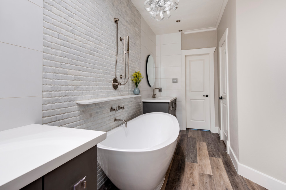 Photo of a classic bathroom in Houston with flat-panel cabinets, grey cabinets, a freestanding bath, white walls, medium hardwood flooring, a submerged sink, beige floors and white worktops.
