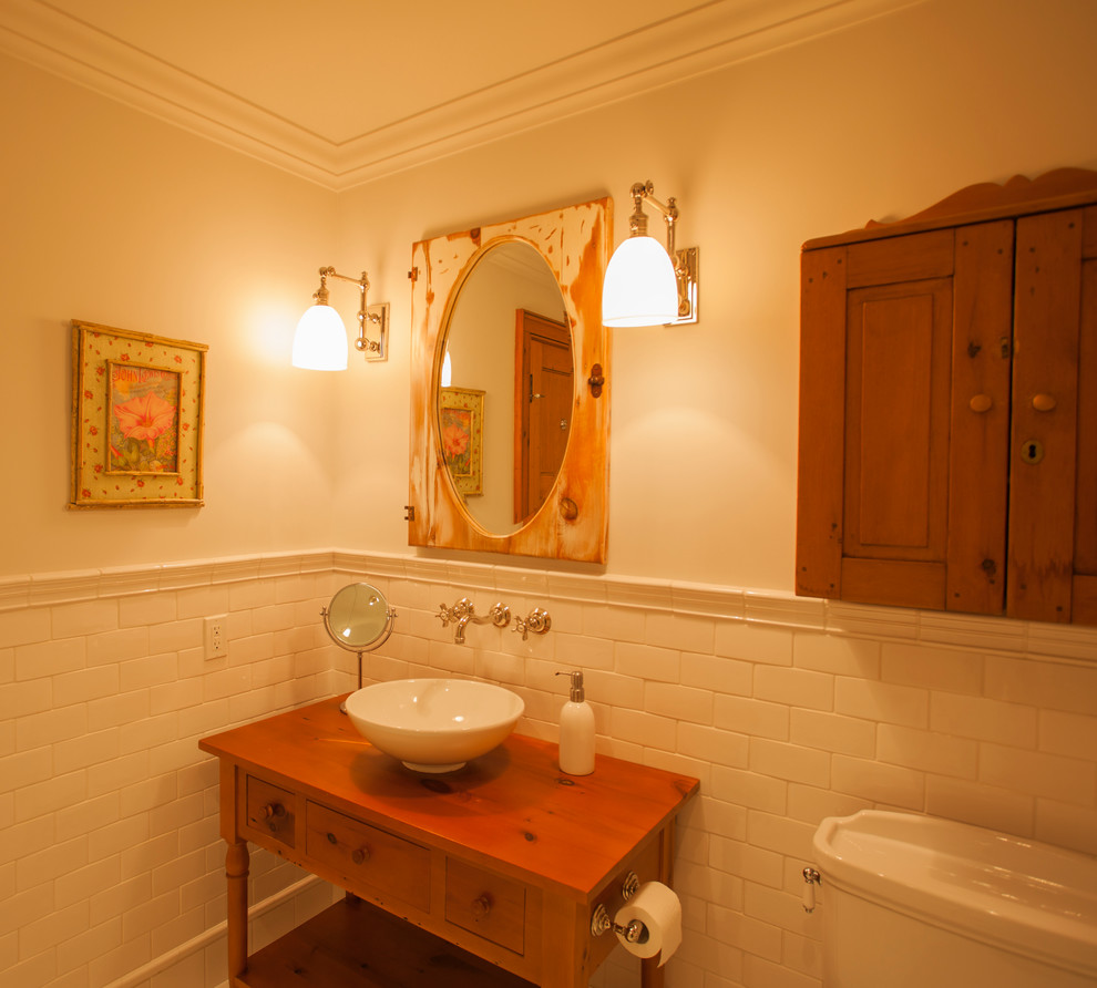 Foto på ett vintage badrum, med ett väggmonterat handfat, öppna hyllor, skåp i mellenmörkt trä, bänkskiva i zink, ett badkar med tassar, en toalettstol med hel cisternkåpa, vit kakel, porslinskakel, vita väggar och mellanmörkt trägolv