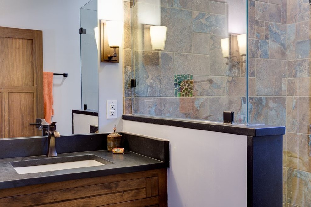 Amerikansk inredning av ett mellanstort en-suite badrum, med luckor med infälld panel, skåp i mörkt trä, våtrum, en toalettstol med separat cisternkåpa, beige kakel, svart kakel, brun kakel, grå kakel, stenkakel, grå väggar, ett undermonterad handfat, bänkskiva i betong och med dusch som är öppen
