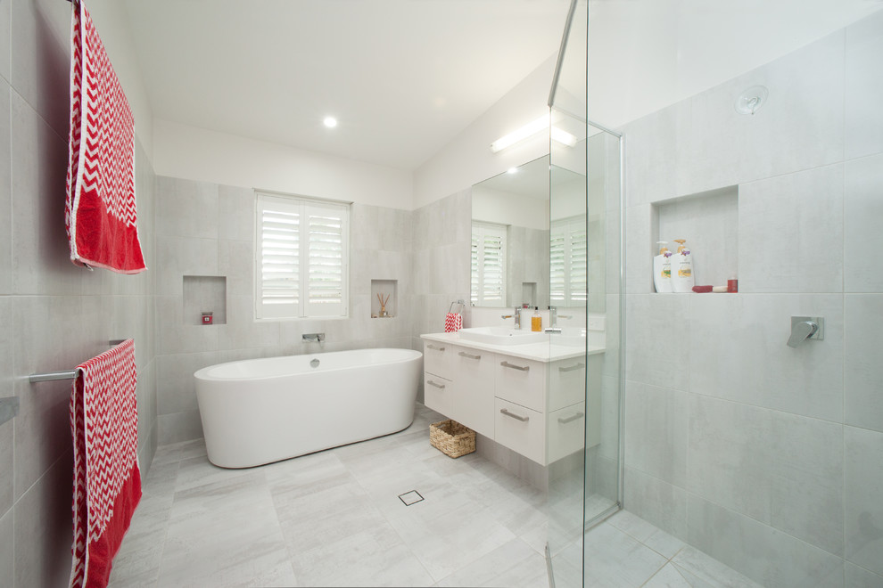 Пример оригинального дизайна: ванная комната в современном стиле с настольной раковиной, плоскими фасадами, белыми фасадами, отдельно стоящей ванной, угловым душем, серой плиткой, керамической плиткой, белыми стенами и полом из керамогранита
