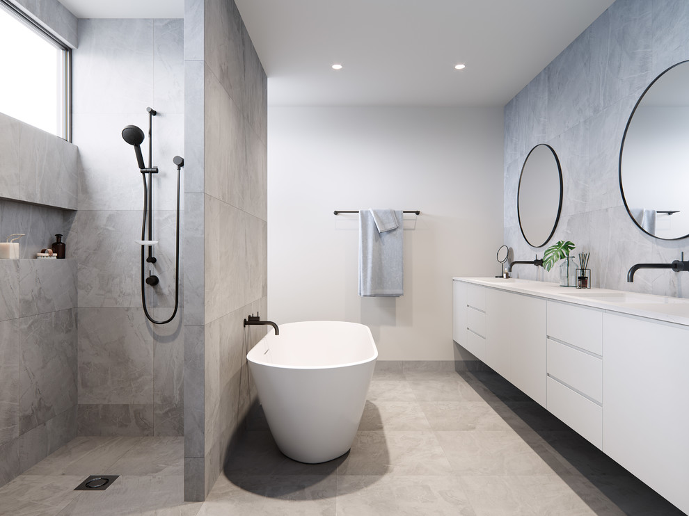 Idée de décoration pour une salle de bain design avec un placard à porte plane, des portes de placard blanches, une baignoire indépendante, un espace douche bain, un carrelage gris, un mur blanc, un lavabo encastré, un sol gris, aucune cabine, un plan de toilette blanc et une fenêtre.