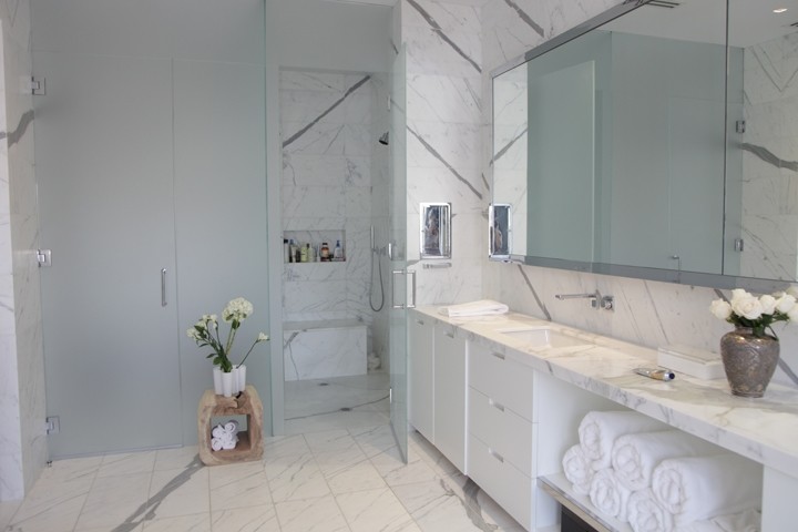 Bild på ett stort retro en-suite badrum, med ett undermonterad handfat, släta luckor, vita skåp, marmorbänkskiva, en dusch i en alkov, vit kakel, stenkakel, vita väggar och marmorgolv