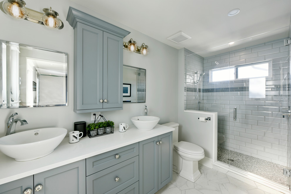 Идея дизайна: главная ванная комната среднего размера в стиле неоклассика (современная классика) с синими фасадами, душем в нише, унитазом-моноблоком, белой плиткой, плиткой кабанчик, настольной раковиной, белым полом, душем с распашными дверями, фасадами с утопленной филенкой и серыми стенами