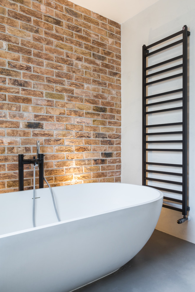 Idee per una stanza da bagno design con vasca freestanding, pareti bianche e pavimento in cemento