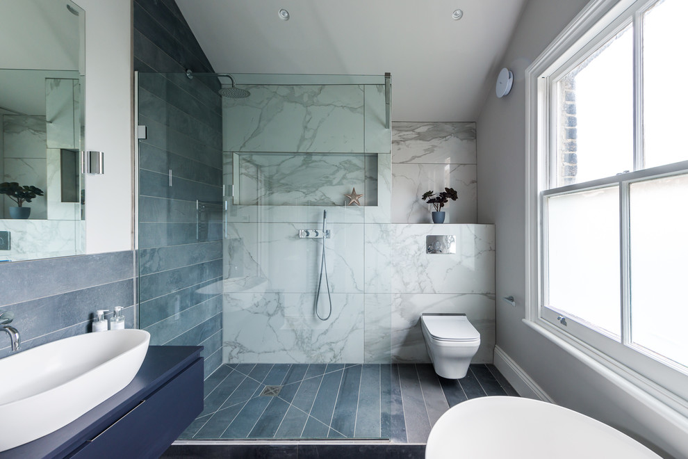 Exemple d'une salle de bain principale tendance de taille moyenne avec des portes de placard bleues, une baignoire indépendante, une douche ouverte, WC à poser, un carrelage noir et blanc, un carrelage de pierre, un mur blanc, un sol en carrelage de céramique et une grande vasque.
