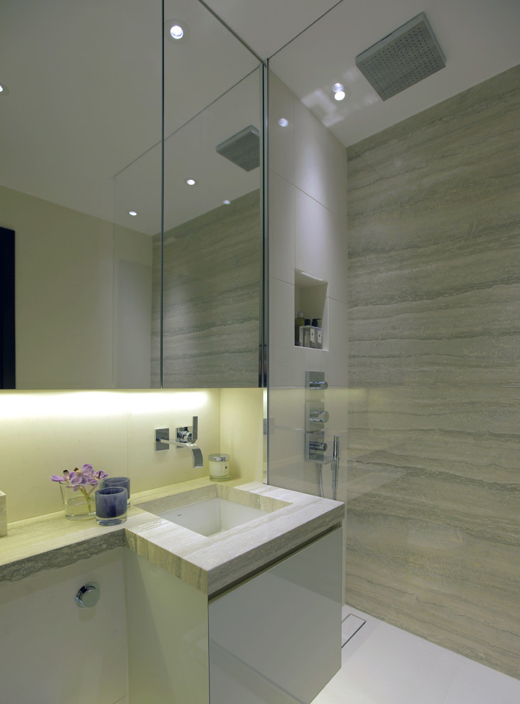 Inredning av ett modernt litet en-suite badrum, med en kantlös dusch, stenhäll, kalkstensgolv, ett undermonterad handfat och bänkskiva i kalksten
