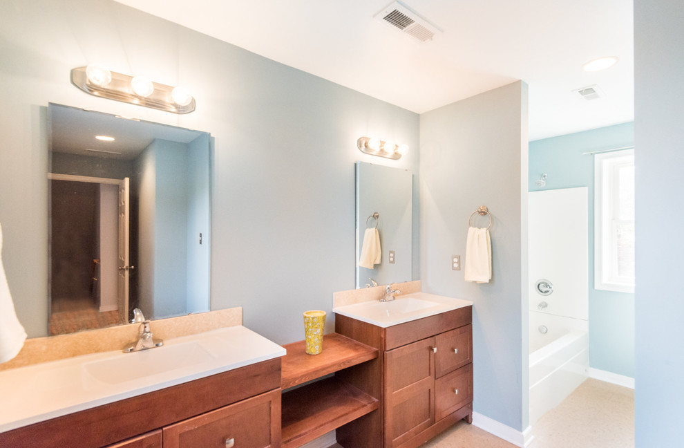 Photo of a small contemporary ensuite bathroom in Wilmington with raised-panel cabinets, medium wood cabinets, a shower/bath combination, a two-piece toilet, blue walls, mosaic tile flooring and an integrated sink.