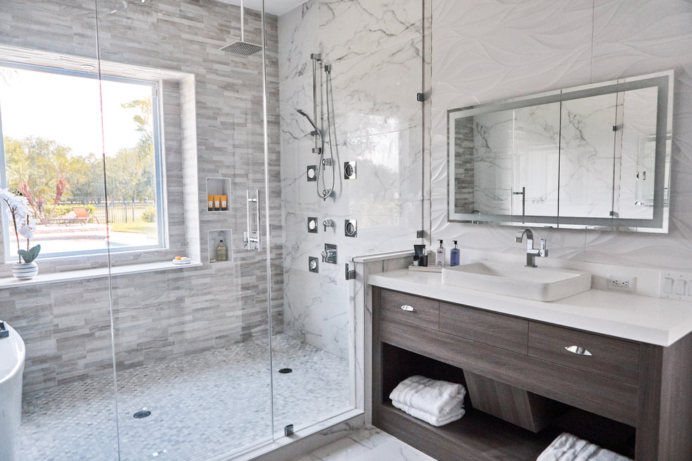 Inspiration for a large contemporary ensuite wet room bathroom in Austin with flat-panel cabinets, dark wood cabinets, a freestanding bath, white tiles, marble tiles, white walls, marble flooring, a vessel sink, solid surface worktops, white floors, a hinged door and white worktops.