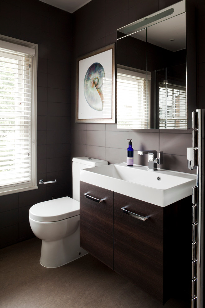 Modernes Badezimmer mit Waschtischkonsole, flächenbündigen Schrankfronten, dunklen Holzschränken, Wandtoilette mit Spülkasten und braunen Fliesen in London