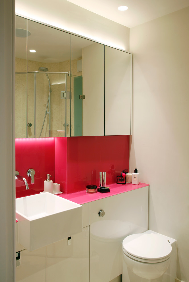 Inspiration pour une salle de bain design avec des portes de placard blanches, un placard à porte plane, un mur blanc et un plan de toilette rose.