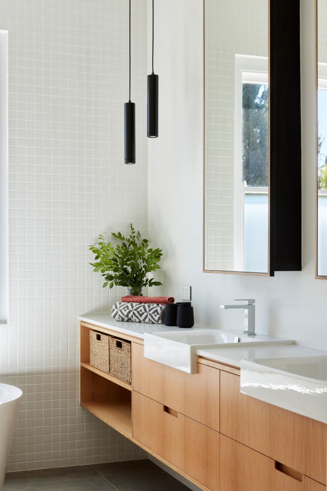 Пример оригинального дизайна: главная ванная комната среднего размера в современном стиле с открытыми фасадами, светлыми деревянными фасадами, отдельно стоящей ванной, унитазом-моноблоком, белой плиткой, керамической плиткой, белыми стенами, полом из керамической плитки, накладной раковиной, серым полом, открытым душем, белой столешницей, тумбой под две раковины, встроенной тумбой, открытым душем и столешницей из искусственного кварца
