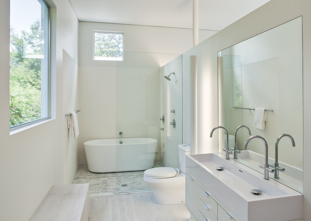 Идея дизайна: главная ванная комната среднего размера в стиле модернизм с плоскими фасадами, белыми фасадами, отдельно стоящей ванной, душем над ванной, раздельным унитазом, разноцветной плиткой, цементной плиткой, белыми стенами, полом из бамбука, подвесной раковиной и столешницей из искусственного камня