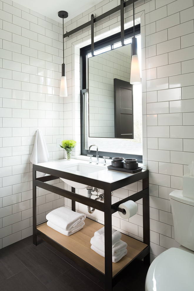 Réalisation d'une salle de bain champêtre avec des portes de placard noires, un carrelage blanc et un lavabo encastré.