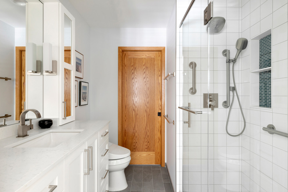 Cette image montre une salle de bain traditionnelle de taille moyenne avec un placard à porte shaker, des portes de placard blanches, WC à poser, un carrelage blanc, des carreaux de porcelaine, un mur blanc, un sol en carrelage de porcelaine, un lavabo encastré, un sol gris, une cabine de douche à porte battante, un plan de toilette blanc, une niche, meuble simple vasque et meuble-lavabo encastré.