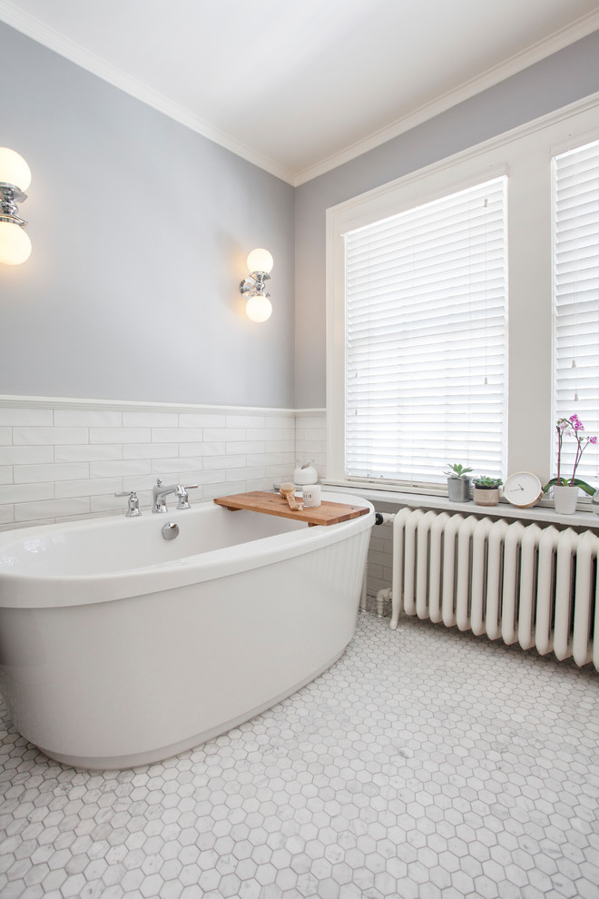 Cette image montre une grande salle de bain principale traditionnelle avec une baignoire indépendante, un carrelage blanc, un carrelage métro, un mur bleu, un sol en marbre et un sol gris.