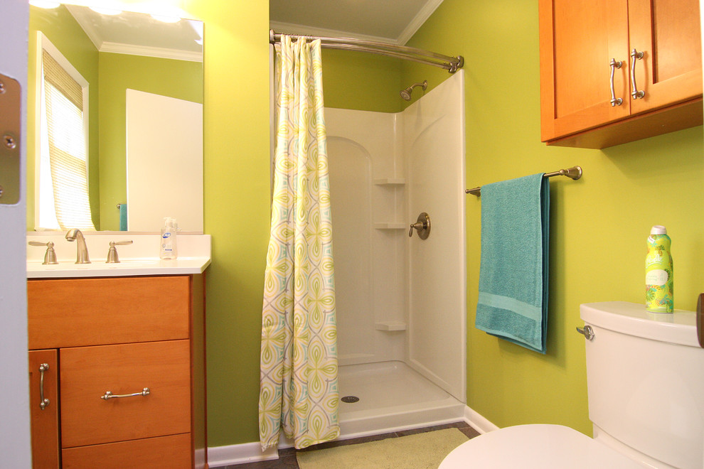 Klassisk inredning av ett litet badrum med dusch, med ett integrerad handfat, släta luckor, skåp i mellenmörkt trä, marmorbänkskiva, en dusch i en alkov, en toalettstol med separat cisternkåpa och gröna väggar
