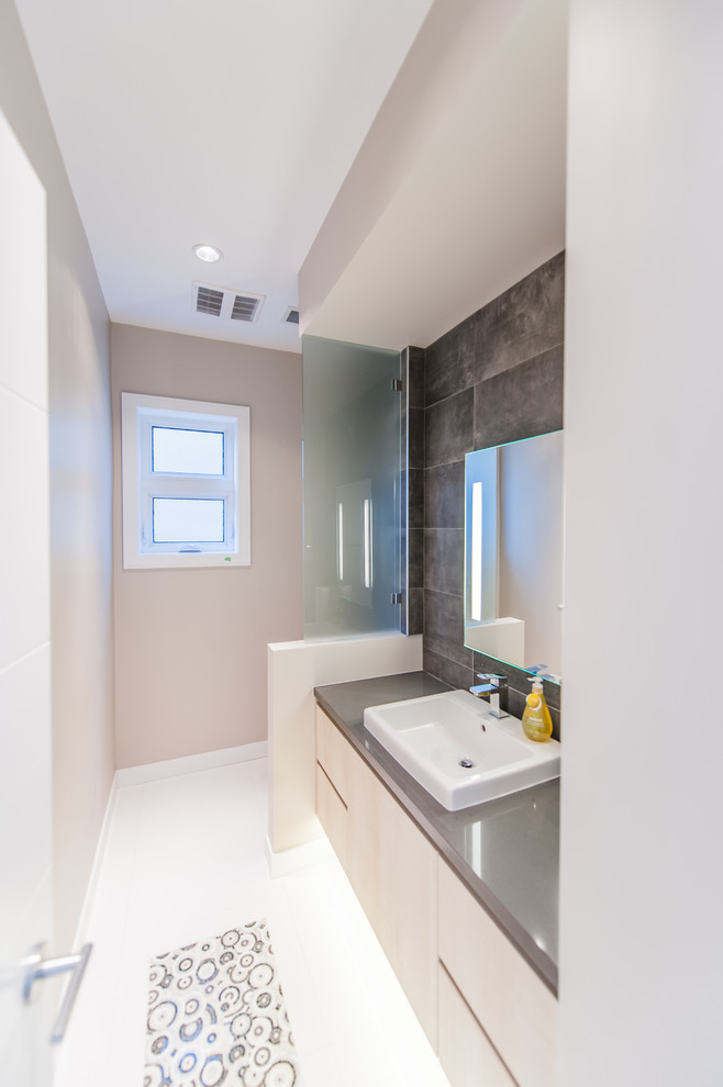 Inspiration for a medium sized modern shower room bathroom in Vancouver with flat-panel cabinets, light wood cabinets, a one-piece toilet, porcelain tiles, beige walls, a vessel sink, engineered stone worktops, grey tiles, porcelain flooring, white floors and grey worktops.