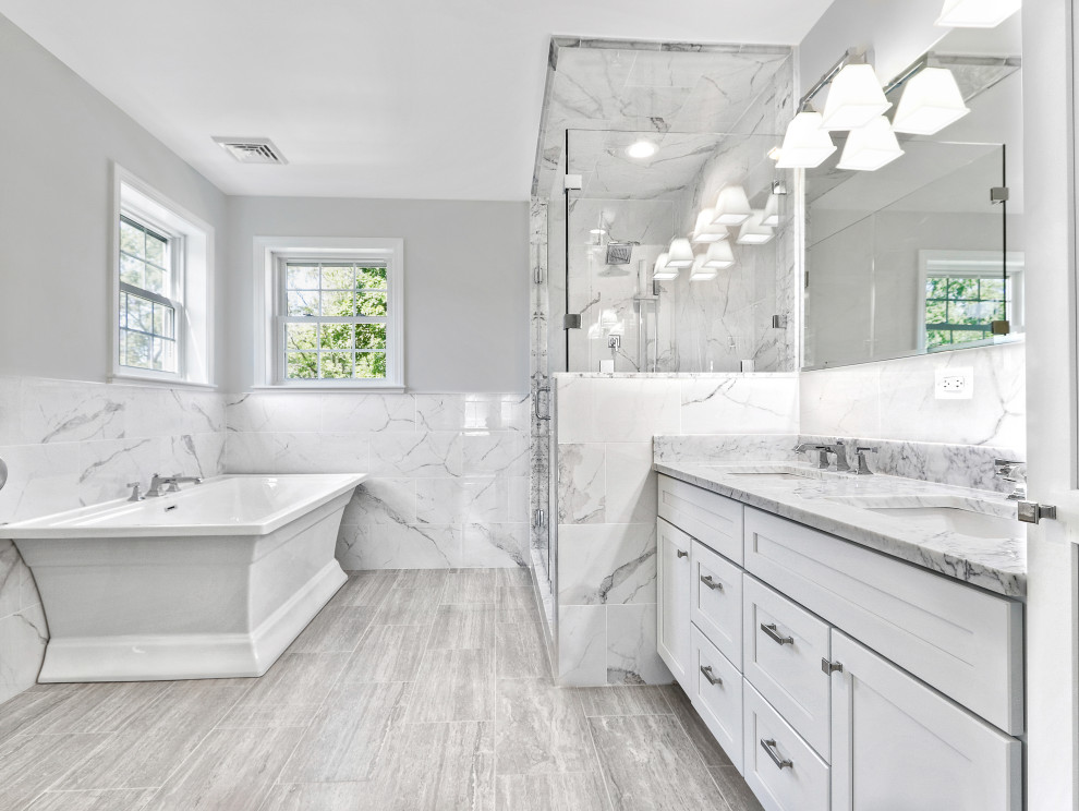 This is an example of a traditional ensuite bathroom in Boston with shaker cabinets, white cabinets, a freestanding bath, an alcove shower, grey tiles, grey walls, a submerged sink, marble worktops, grey floors, a hinged door, grey worktops, double sinks and a built in vanity unit.