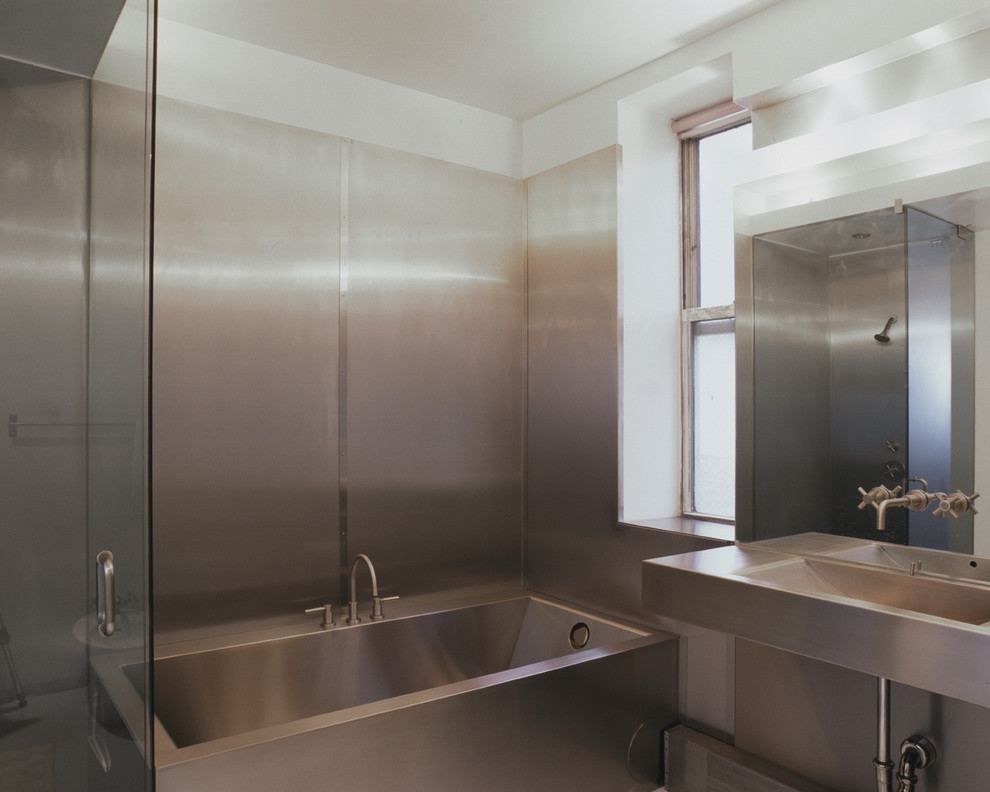 Diseño de cuarto de baño urbano de tamaño medio con bañera empotrada, ducha empotrada, lavabo integrado y encimera de acero inoxidable