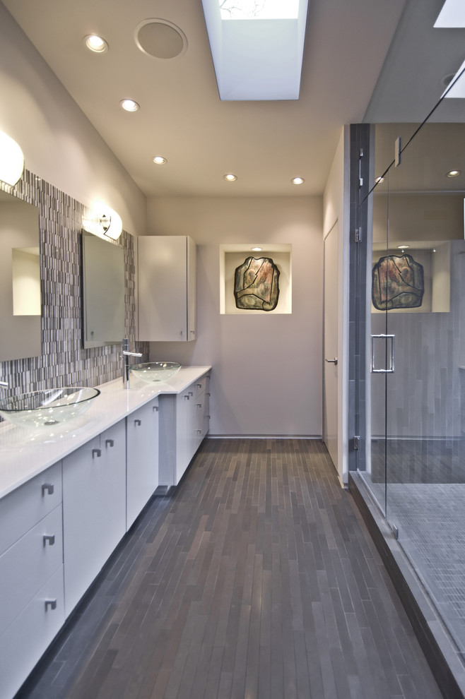 На фото: главная ванная комната среднего размера в стиле модернизм с настольной раковиной, плоскими фасадами, белыми фасадами, накладной ванной, открытым душем, разноцветной плиткой, удлиненной плиткой, серыми стенами и полом из известняка с