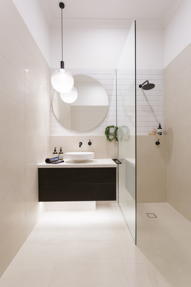 Cette image montre une salle d'eau minimaliste de taille moyenne avec un placard à porte affleurante, des portes de placard noires, une douche ouverte, des carreaux de béton, une vasque, un plan de toilette en acier inoxydable et un plan de toilette blanc.