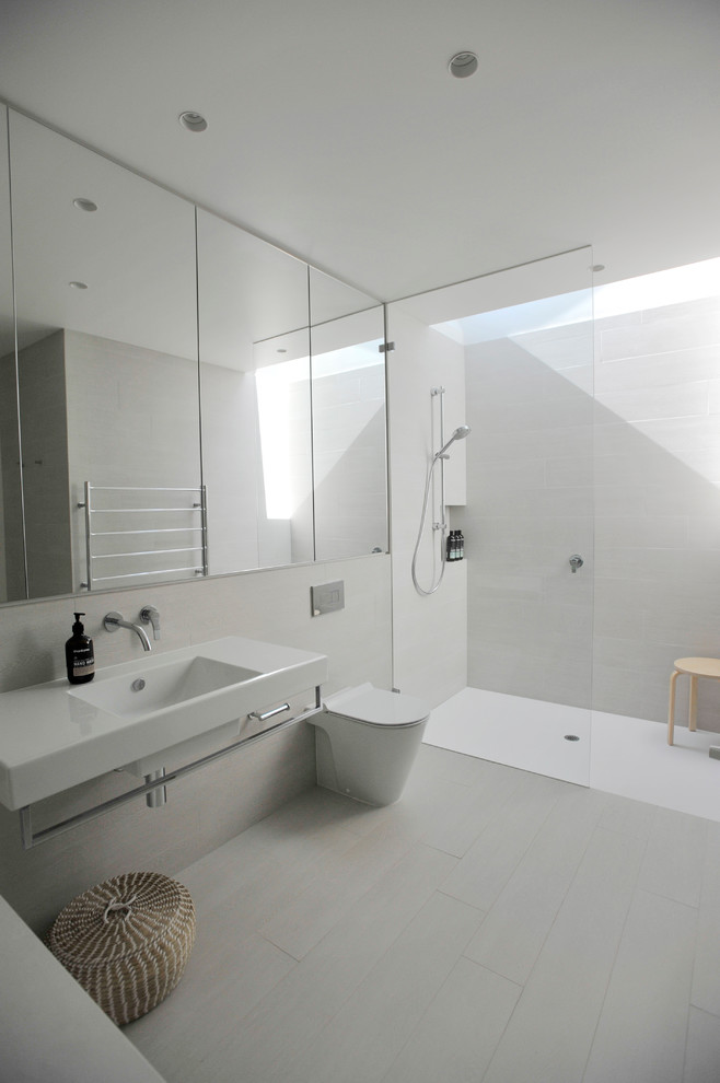 Modelo de cuarto de baño contemporáneo de tamaño medio con sanitario de una pieza, paredes blancas, lavabo integrado, bañera encastrada, baldosas y/o azulejos grises, baldosas y/o azulejos de porcelana y ducha a ras de suelo