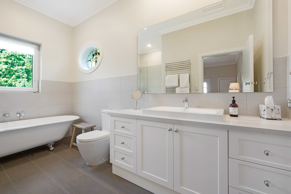 Foto di una stanza da bagno padronale minimal di medie dimensioni con ante in stile shaker, ante bianche, vasca con piedi a zampa di leone, WC monopezzo, piastrelle grigie e pareti bianche