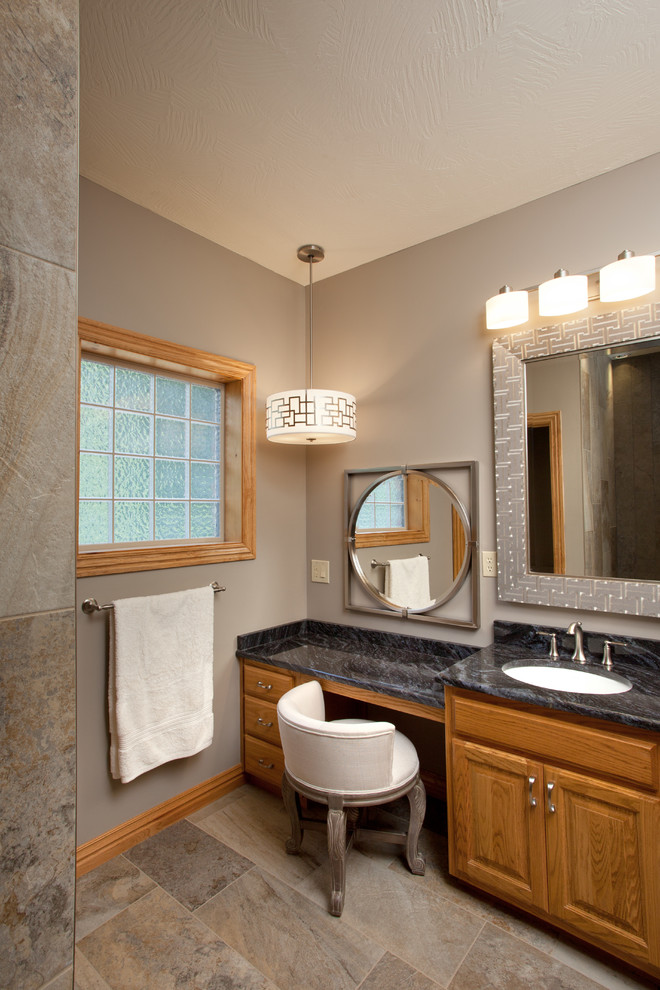 Exempel på ett litet klassiskt en-suite badrum, med luckor med upphöjd panel, skåp i mellenmörkt trä, en kantlös dusch, en toalettstol med hel cisternkåpa, beige kakel, stenkakel, grå väggar, ett undermonterad handfat och granitbänkskiva