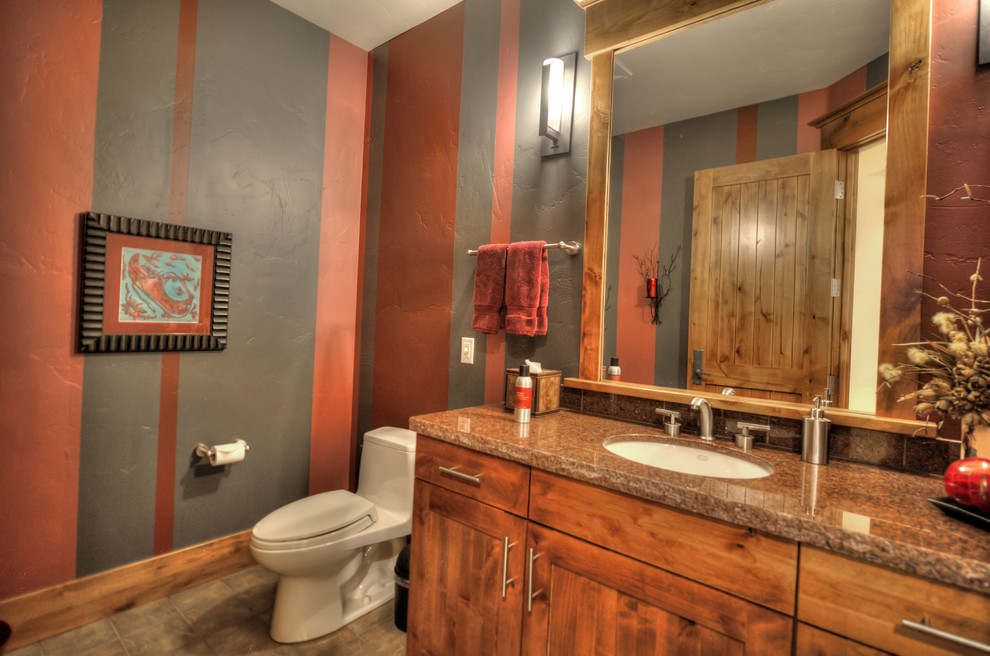 Rustik inredning av ett mellanstort badrum, med luckor med infälld panel, skåp i mellenmörkt trä, en toalettstol med separat cisternkåpa, flerfärgad kakel, flerfärgade väggar, ett undermonterad handfat och granitbänkskiva