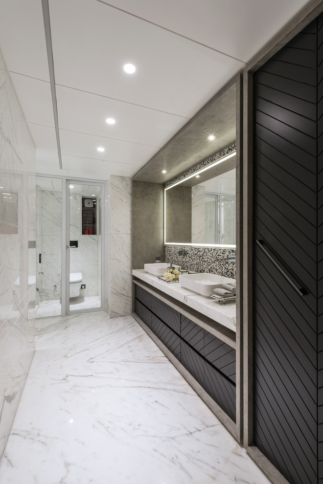 Idées déco pour une salle de bain contemporaine avec un placard à porte plane, des portes de placard noires, WC à poser, un carrelage noir et blanc, un carrelage gris, un carrelage multicolore, mosaïque, un mur blanc, une vasque, un sol blanc et un plan de toilette blanc.