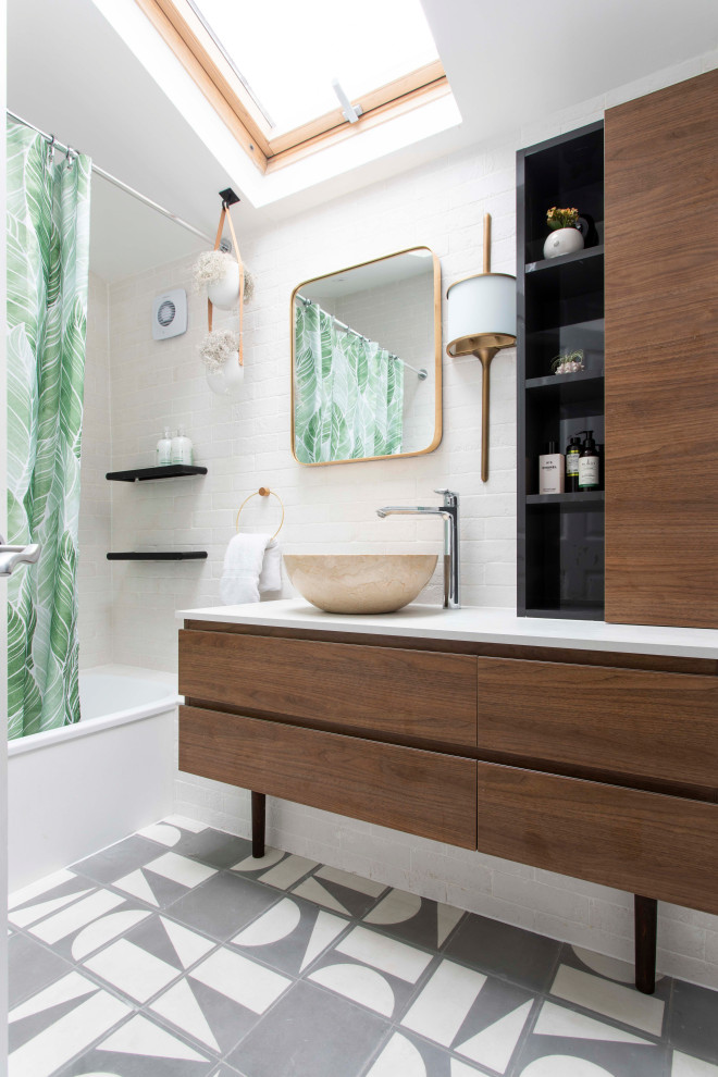 На фото: ванная комната в современном стиле с плоскими фасадами, фасадами цвета дерева среднего тона, ванной в нише, душем над ванной, белой плиткой, белыми стенами, душевой кабиной, настольной раковиной, разноцветным полом, шторкой для ванной и белой столешницей