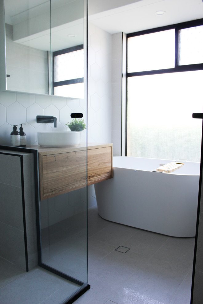 This is an example of a small modern family bathroom in Perth with freestanding cabinets, dark wood cabinets, a freestanding bath, a corner shower, white tiles, mosaic tiles, white walls, porcelain flooring, a vessel sink, wooden worktops, grey floors, a hinged door and brown worktops.