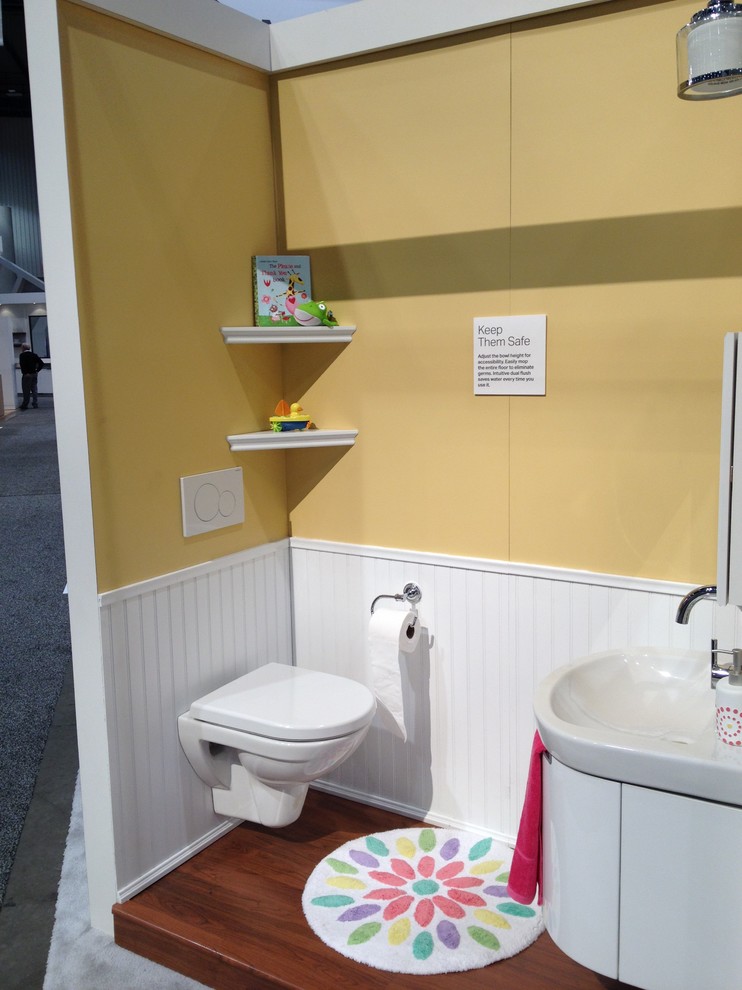 Imagen de cuarto de baño infantil contemporáneo pequeño con lavabo suspendido, sanitario de pared, paredes amarillas y suelo de madera oscura