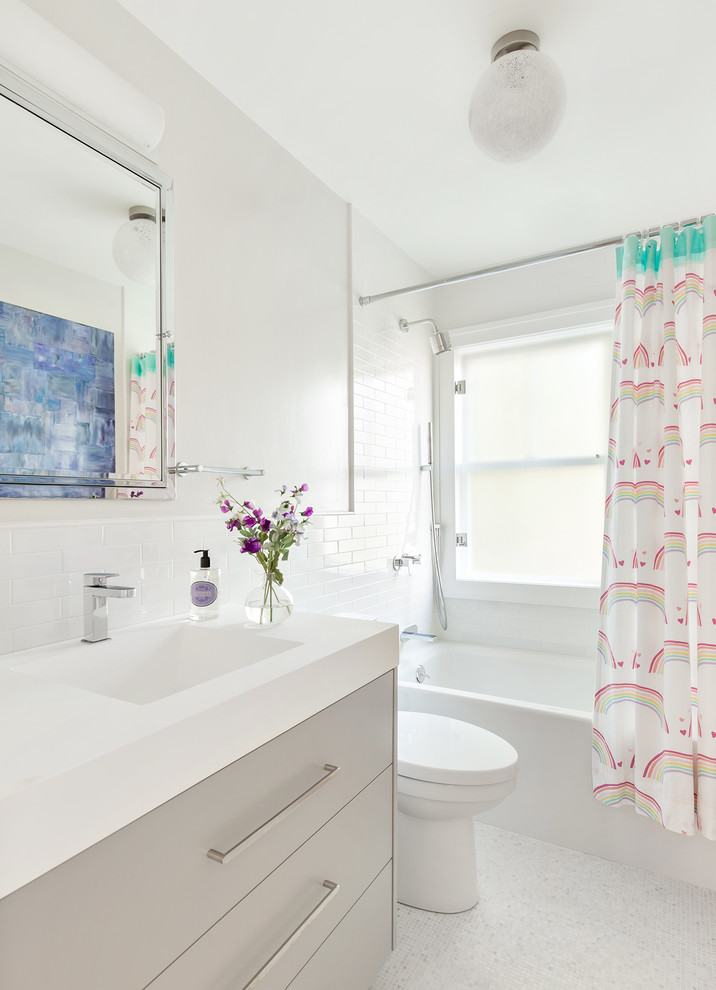 Inspiration for a traditional family bathroom in New York with flat-panel cabinets, grey cabinets, an alcove bath, a shower/bath combination, white tiles, metro tiles, white walls, mosaic tile flooring, an integrated sink and a shower curtain.