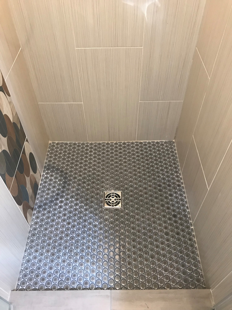 Medium sized modern family bathroom in Milwaukee with flat-panel cabinets, light wood cabinets, an alcove bath, an alcove shower, a one-piece toilet, beige tiles, porcelain tiles, blue walls, porcelain flooring, a vessel sink, quartz worktops, grey floors, a hinged door and blue worktops.