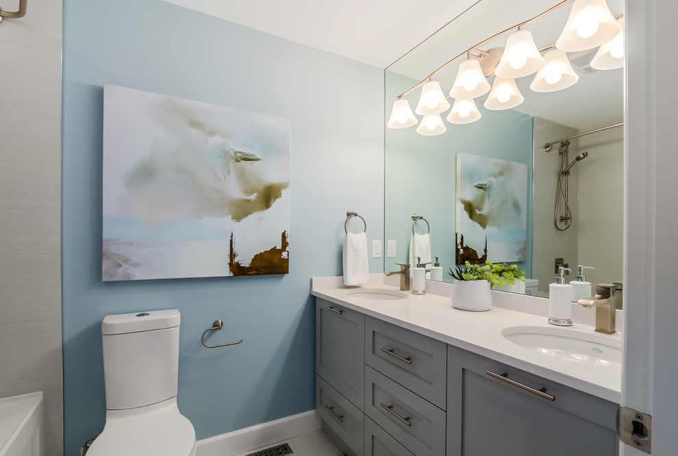 Пример оригинального дизайна: ванная комната среднего размера в стиле неоклассика (современная классика) с фасадами в стиле шейкер, серыми фасадами, бежевой плиткой, керамической плиткой, полом из керамической плитки, ванной в нише, душем над ванной, раздельным унитазом, синими стенами, врезной раковиной и зеркалом с подсветкой