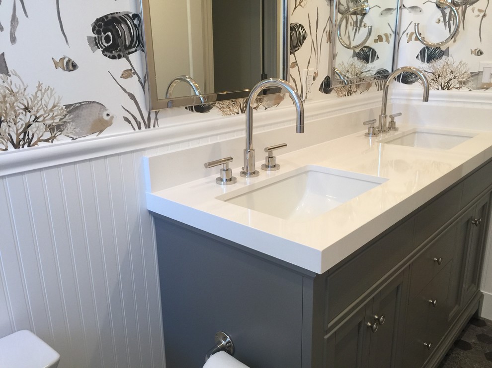 Photo of a medium sized coastal family bathroom in San Francisco with recessed-panel cabinets, grey cabinets, an alcove bath, a shower/bath combination, a one-piece toilet, white tiles, multi-coloured walls, a submerged sink, solid surface worktops, multi-coloured floors, a shower curtain, white worktops, metro tiles, marble flooring, a wall niche, double sinks, a built in vanity unit and wallpapered walls.