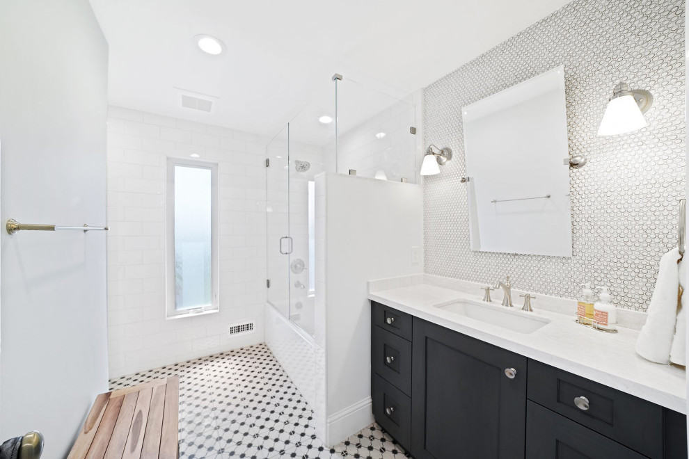На фото: большая ванная комната в стиле неоклассика (современная классика) с фасадами в стиле шейкер, черными фасадами, ванной в нише, душем над ванной, серой плиткой, белой плиткой, керамогранитной плиткой, белыми стенами, душевой кабиной, врезной раковиной, разноцветным полом, душем с распашными дверями, белой столешницей, тумбой под одну раковину и встроенной тумбой с