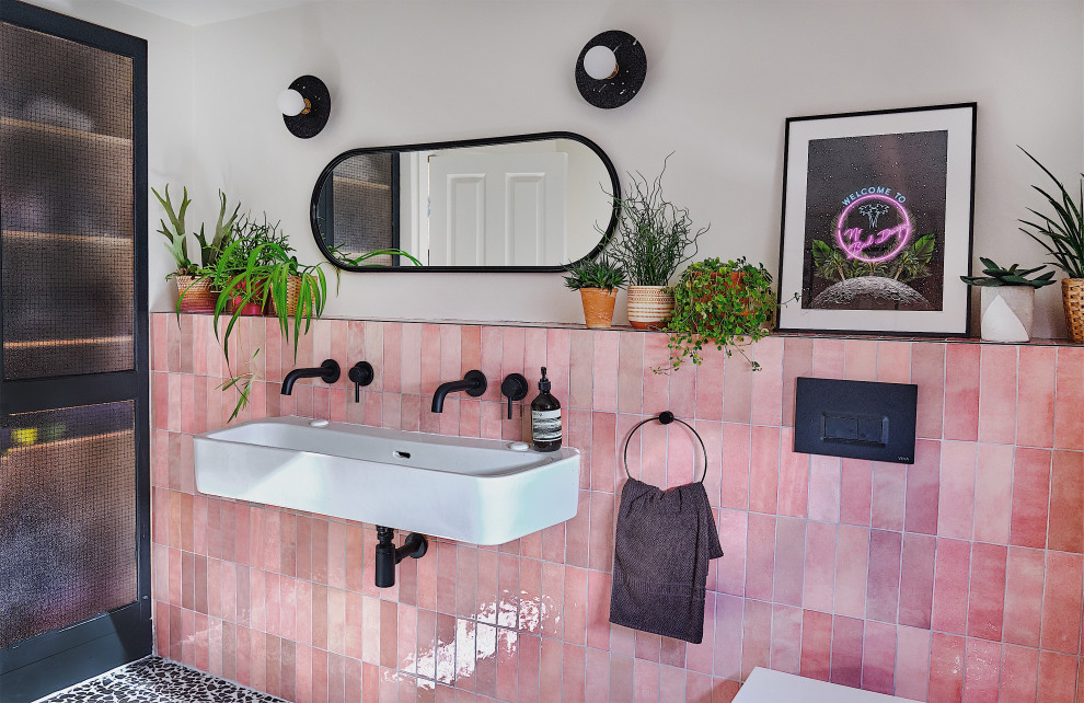 Inspiration for a medium sized contemporary family bathroom in London with black cabinets, a walk-in shower, a wall mounted toilet, pink tiles, ceramic tiles, white walls, terrazzo flooring, a trough sink, black floors, an open shower, a wall niche and a single sink.