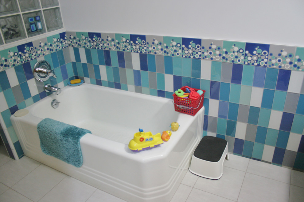 Exemple d'une salle de bain moderne en bois brun de taille moyenne pour enfant avec un placard à porte plane, un plan de toilette en surface solide, une baignoire indépendante, un carrelage bleu, un carrelage en pâte de verre, un mur bleu et un sol en carrelage de céramique.