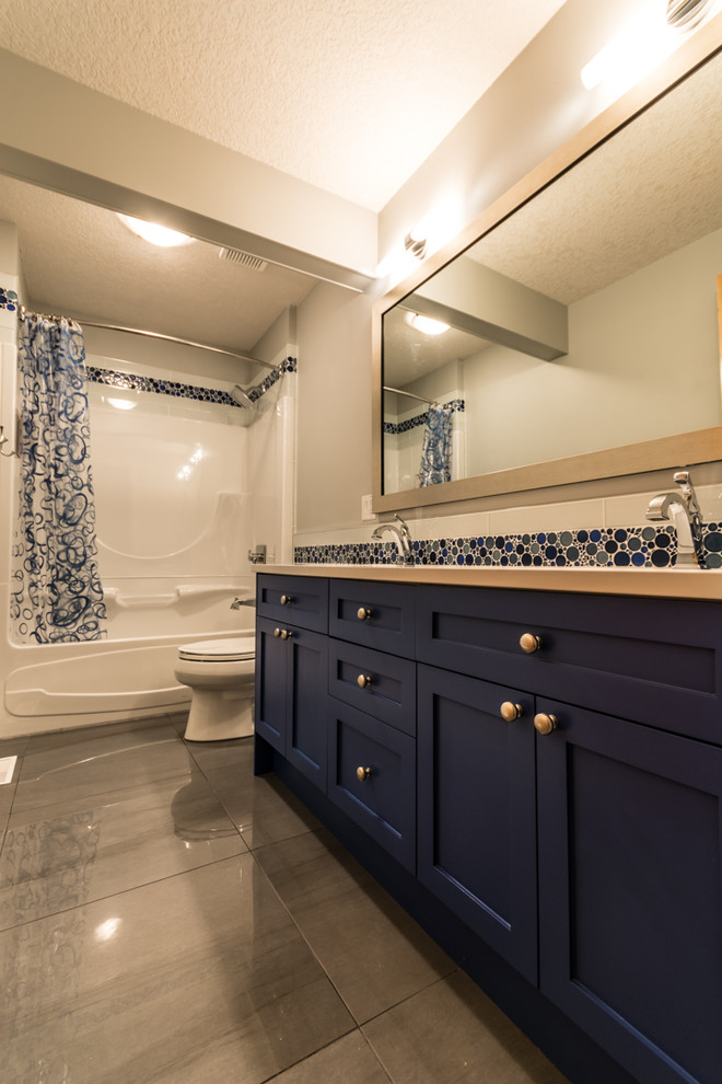 Esempio di una stanza da bagno classica di medie dimensioni con lavabo sottopiano, ante in stile shaker, ante blu, top in quarzo composito, vasca ad alcova, vasca/doccia, WC a due pezzi, piastrelle blu, piastrelle di vetro, pareti grigie e pavimento in gres porcellanato