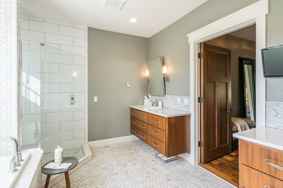 На фото: главная ванная комната в стиле неоклассика (современная классика) с плоскими фасадами, фасадами цвета дерева среднего тона, угловым душем, белой плиткой, серыми стенами, полом из мозаичной плитки и серым полом