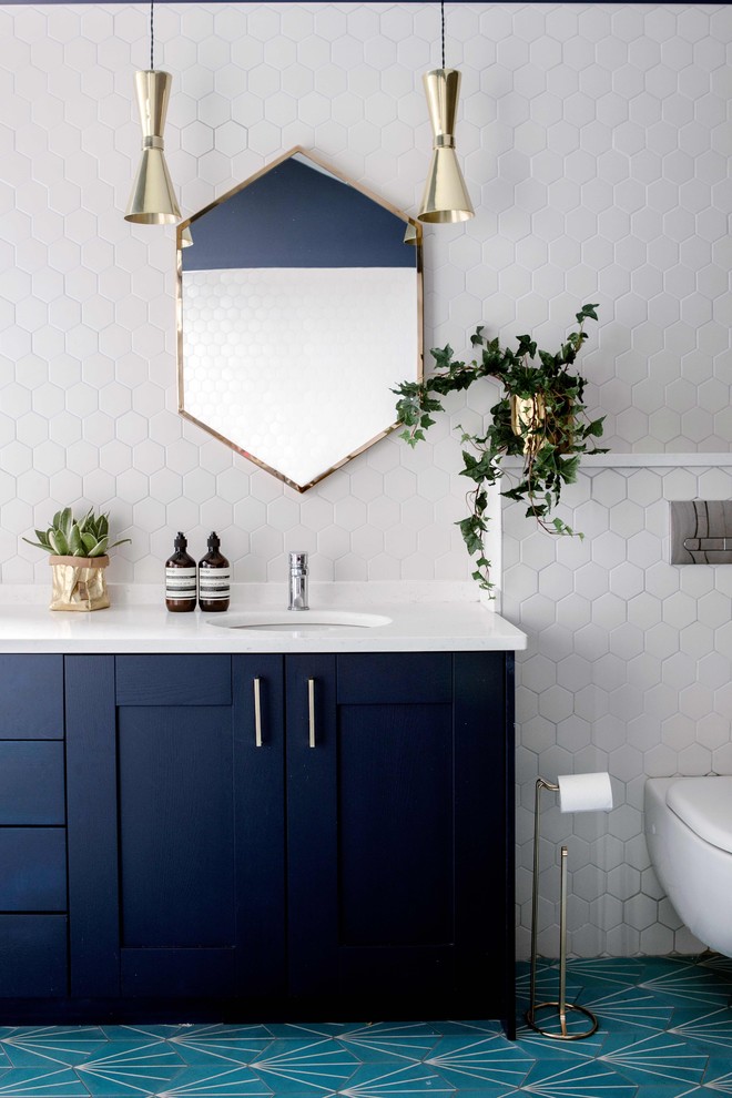 Modernes Badezimmer mit flächenbündigen Schrankfronten, blauen Schränken, Wandtoilette, weißen Fliesen, weißer Wandfarbe, Unterbauwaschbecken, blauem Boden und weißer Waschtischplatte in Sonstige