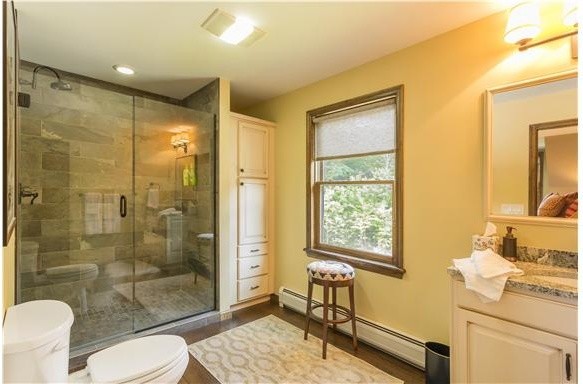 Immagine di una stanza da bagno padronale stile rurale di medie dimensioni con ante bianche, top in granito, doccia ad angolo, piastrelle multicolore, pareti gialle e pavimento in legno massello medio