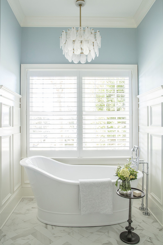 Imagen de cuarto de baño tradicional con bañera exenta, paredes azules y suelo blanco